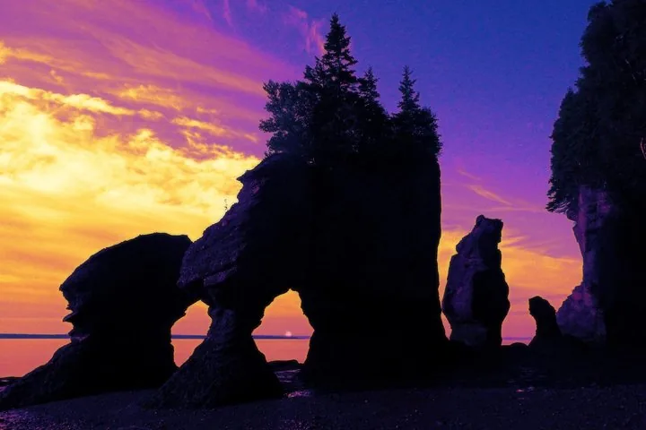 Rocce a vaso in silhouette contro un cielo vibrante al tramonto al Parco provinciale Hopewell Rocks.